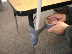 a person holding a can under a table with a metal base and legs on it