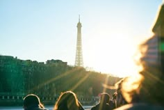 people are watching the sun set in front of the eiffel tower, paris