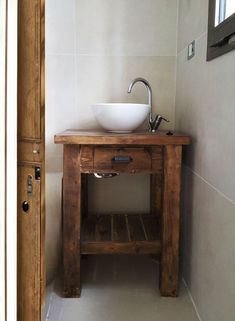 a wooden table with a white bowl on it in a small room next to a door