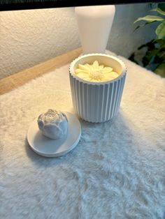 a white vase sitting on top of a table next to a bowl filled with food