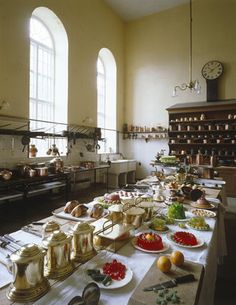 a large table with many plates and bowls on it in front of two arched windows