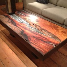 a coffee table made out of wood and pebbles on the floor in front of a couch