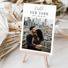 an easer holds a photo of a couple in new york, with the city skyline behind them