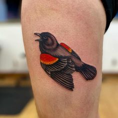 a small bird tattoo on the right thigh, with an orange and black stripe around it