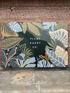 a large painting on the side of a brick building that says plant daddy co in front of it