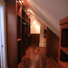 an attic bedroom with wooden floors and built - in shelving