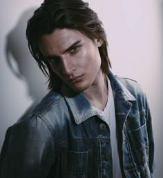 a man with long hair wearing a denim jacket