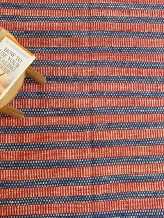 a book sitting on top of a wooden chair next to a red and blue rug