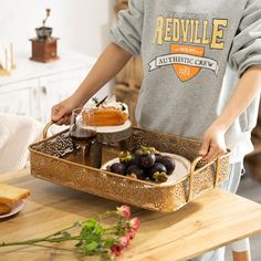 a person standing over a wooden table with food in a metal tray on top of it