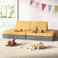 a toy monkey sitting on top of a yellow couch next to wooden blocks and toys