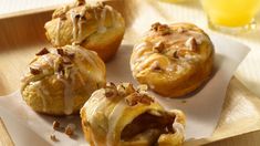 four pastries are sitting on a plate with icing and nuts around them, ready to be eaten