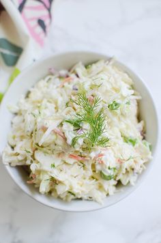 a white bowl filled with coleslaw and garnished with dilled sprigs