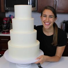 a woman sitting in front of a large white cake