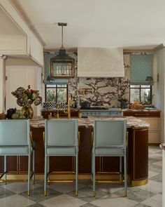 a kitchen with marble counter tops and blue chairs