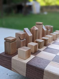 a close up of a chess board with wooden pieces on it and grass in the background