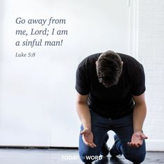 a man kneeling down in front of a white wall with a bible verse written on it