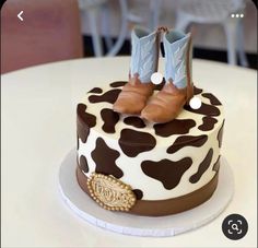 a cake decorated with brown and white cow print, cowboy boots on top of it