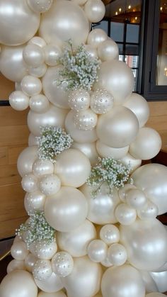 white balloons and baby's breath flowers are arranged in the shape of a tower