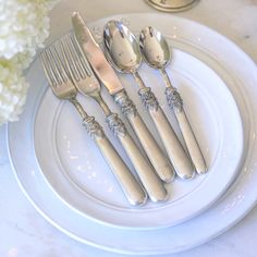 four silverware on a white plate with flowers in the background