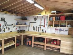 a workbench with lots of tools hanging on the wall and shelves above it