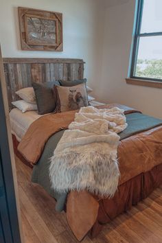 a bedroom with a large bed covered in blankets and pillows next to a wooden headboard