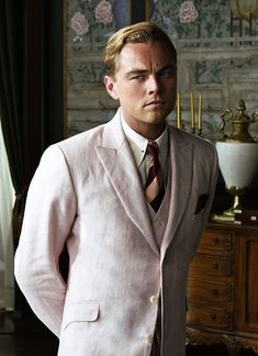 a man in a suit standing next to a dresser