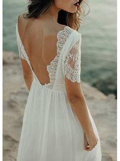 the back of a woman's wedding dress, with lace detailing and open shoulders