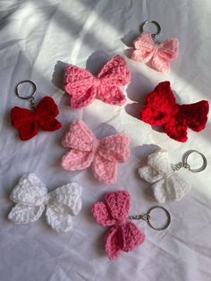 six crocheted bows are arranged on a white sheet with silver keychains