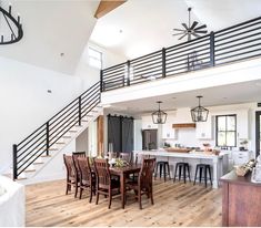 a large open floor plan with wooden floors and black railings on the upper level