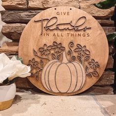 a wooden sign that says give peace in all things with a pumpkin and flowers on it