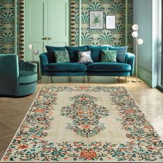 a living room filled with blue couches next to a green chair and wallpaper