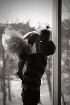 a woman standing in front of a window with a stuffed animal on her shoulder and tutu skirt