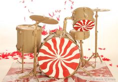 a red and white candy cane drum set on top of a striped tablecloth with confetti in the background