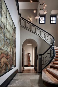 a staircase leading up to a large painting on the wall in a home with marble floors