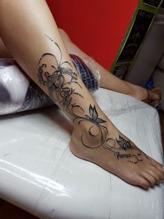 a woman sitting on top of a table with a tattoo on her leg and foot