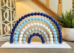 an arch made out of blue and white beads sits on a table next to a potted plant