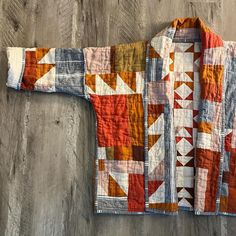 an orange and white quilted jacket sitting on top of a wooden floor next to a wall