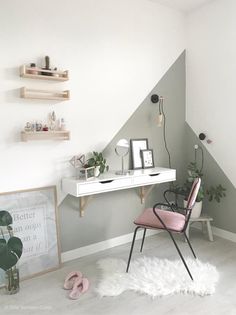 a white desk sitting under a slanted wall in a room with shelves on it