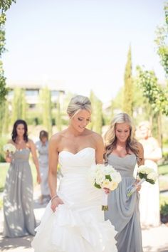 two bridesmaids are walking down the aisle with their bouquets in hand and one is wearing a strapless wedding dress