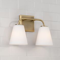 two light bathroom fixture with white glass shades on the wall and brick back splash behind it