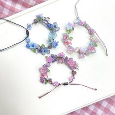 three bracelets made out of glass beads on a white board with pink and blue checkered table cloth