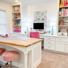 a desk with two stools in front of it and a television on the wall