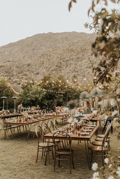 tables and chairs set up for an outdoor dinner in the desert with mountains in the background