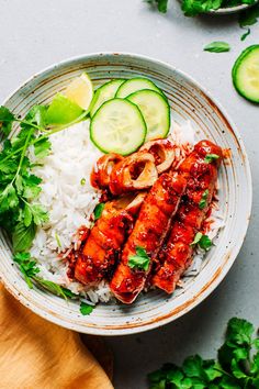 a bowl filled with rice, cucumber slices and other food on top of it