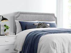 a bed with blue and white comforter in a bedroom next to a lamp on a nightstand