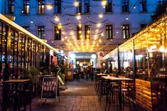 an outdoor restaurant with lights strung from the ceiling