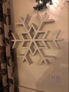 a snowflake is hanging on the wall next to a light switch and curtain