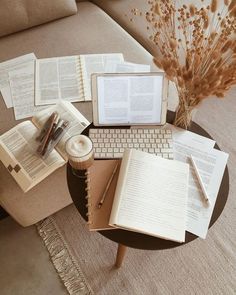 a table topped with open books next to a laptop computer