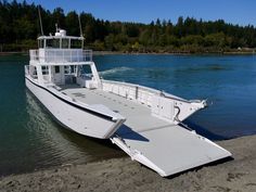 a white boat sitting on top of a beach next to the ocean with trees in the background