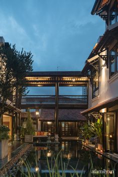 an outdoor area with water and plants at dusk, lit up by lights on the ceiling